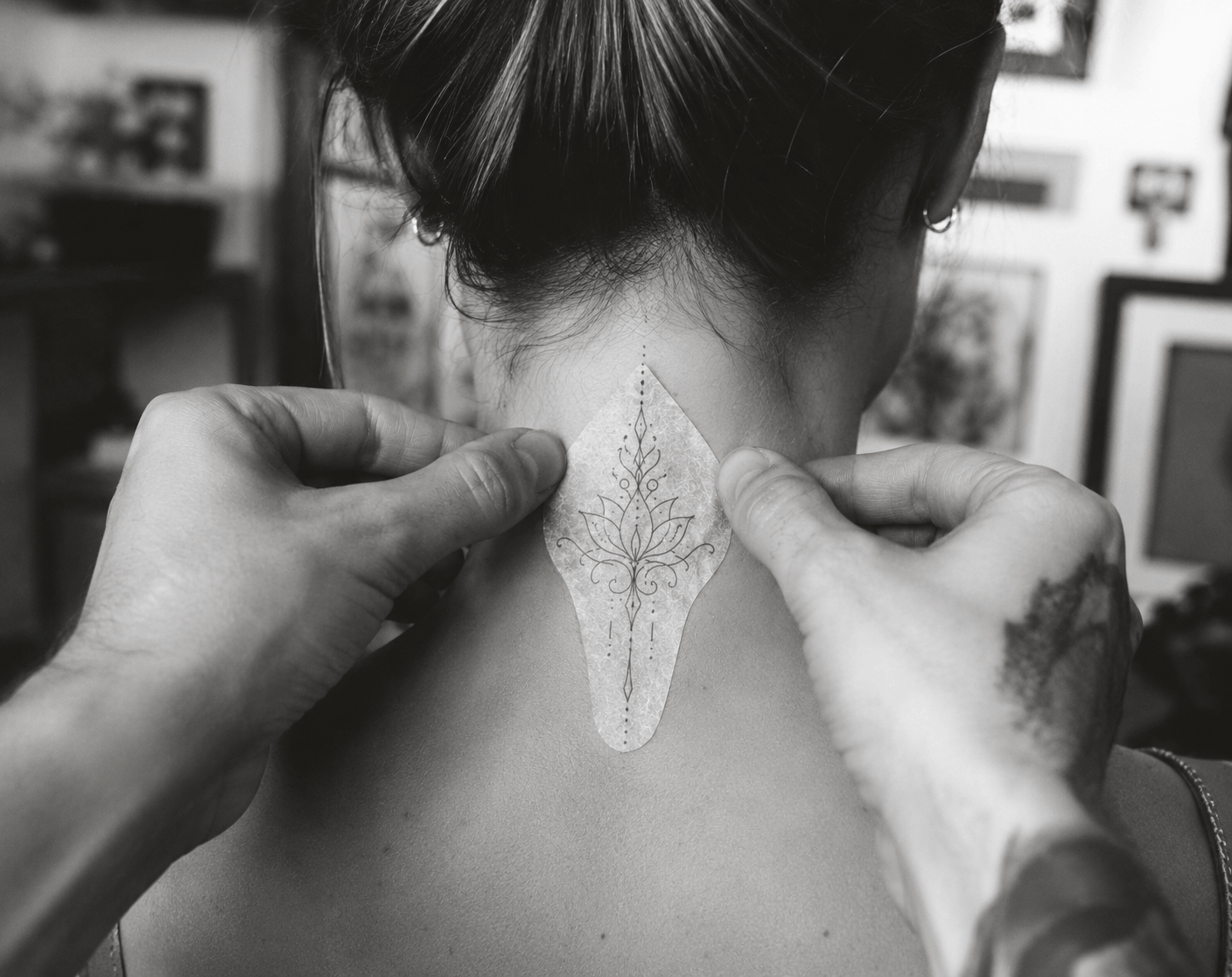 Tatoueur positionnant un stencil floral au centre de la nuque