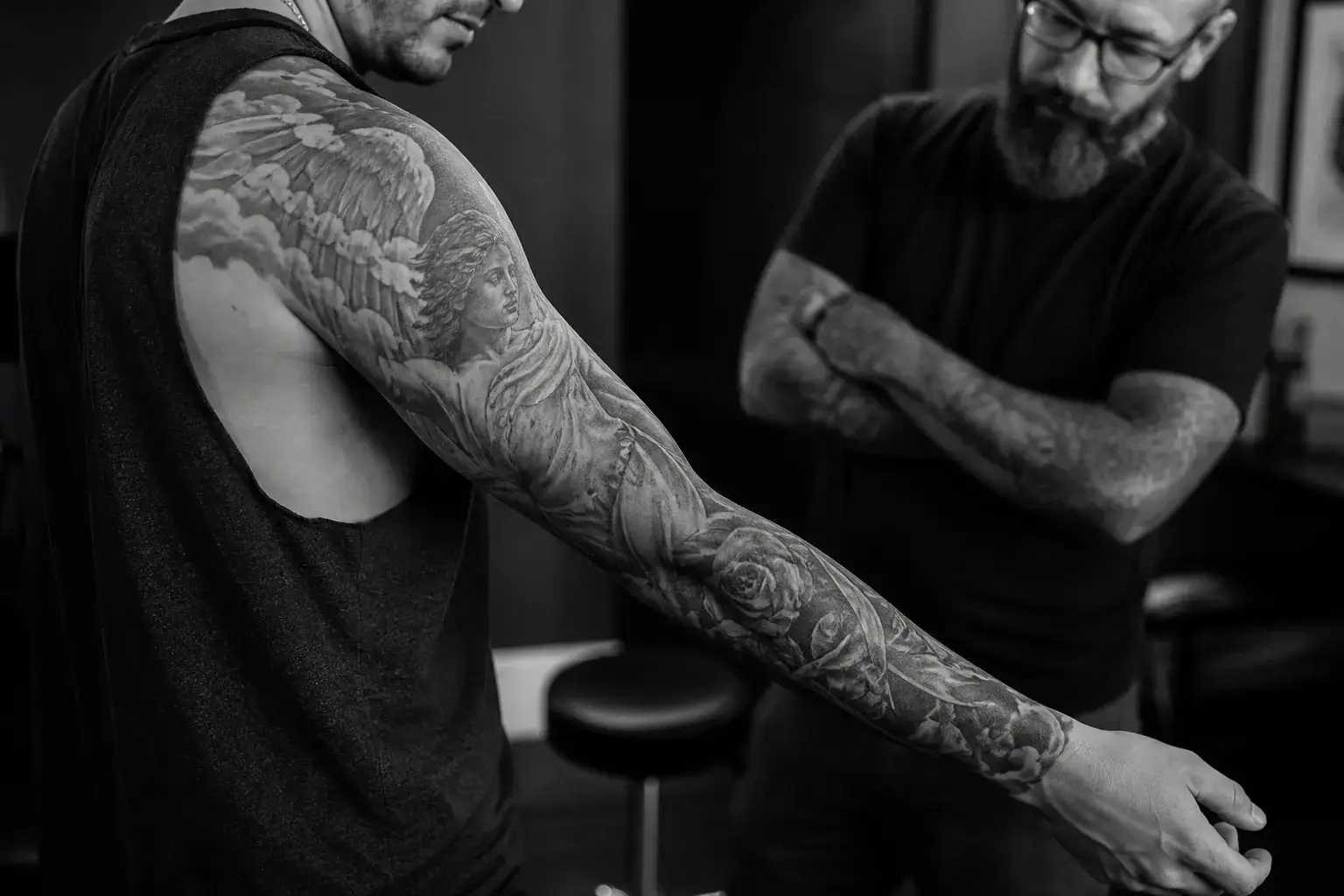 Tatouage noir et gris cicatrisé suivant l’épaule, le bras et l’avant-bras