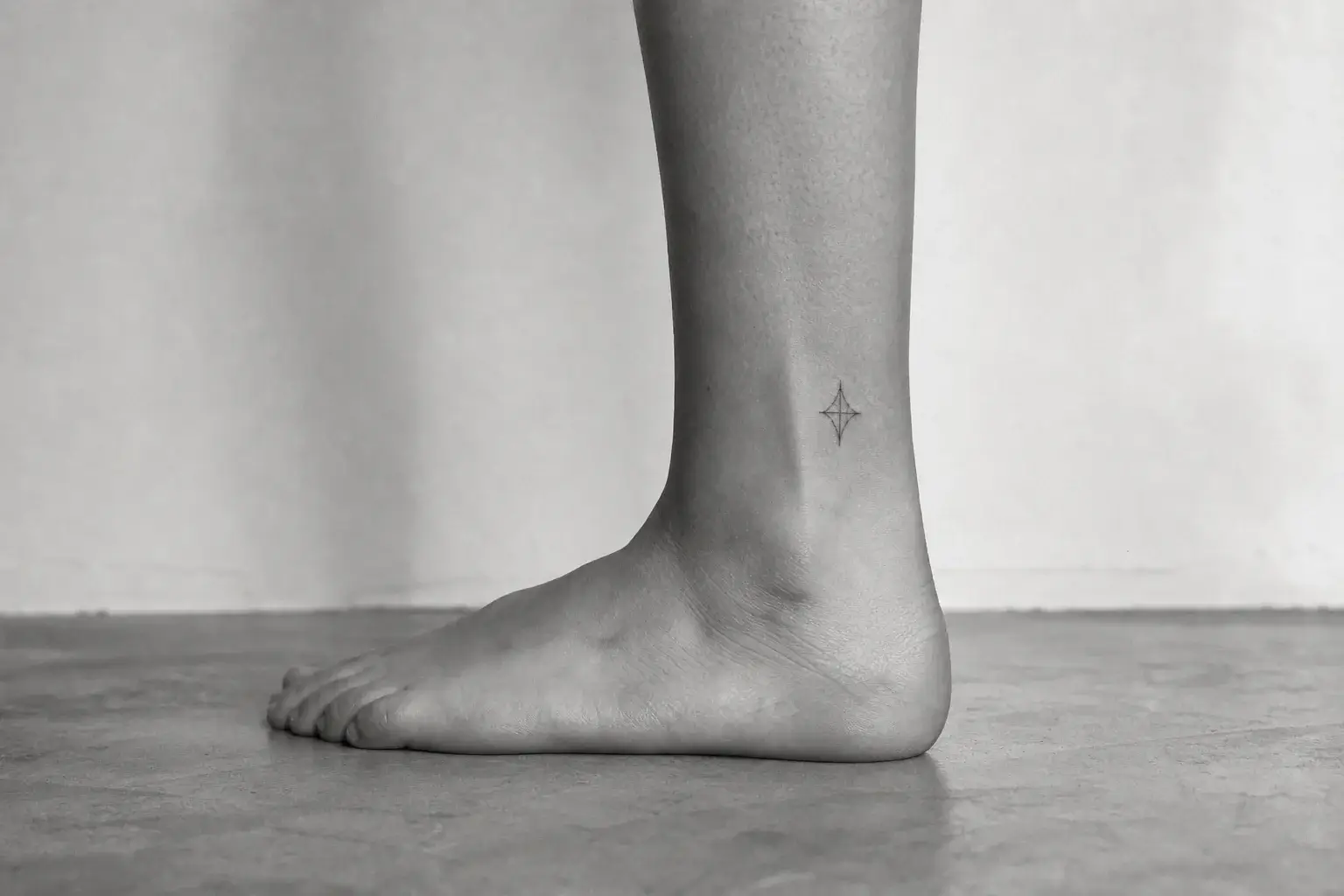 Petit motif géométrique fin tatoué au-dessus de la cheville