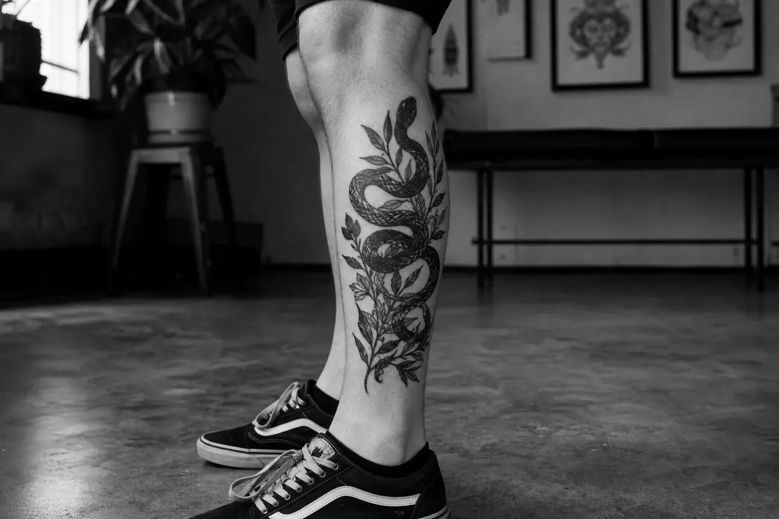 Tatouage de serpent et feuillage en blackwork sur un mollet