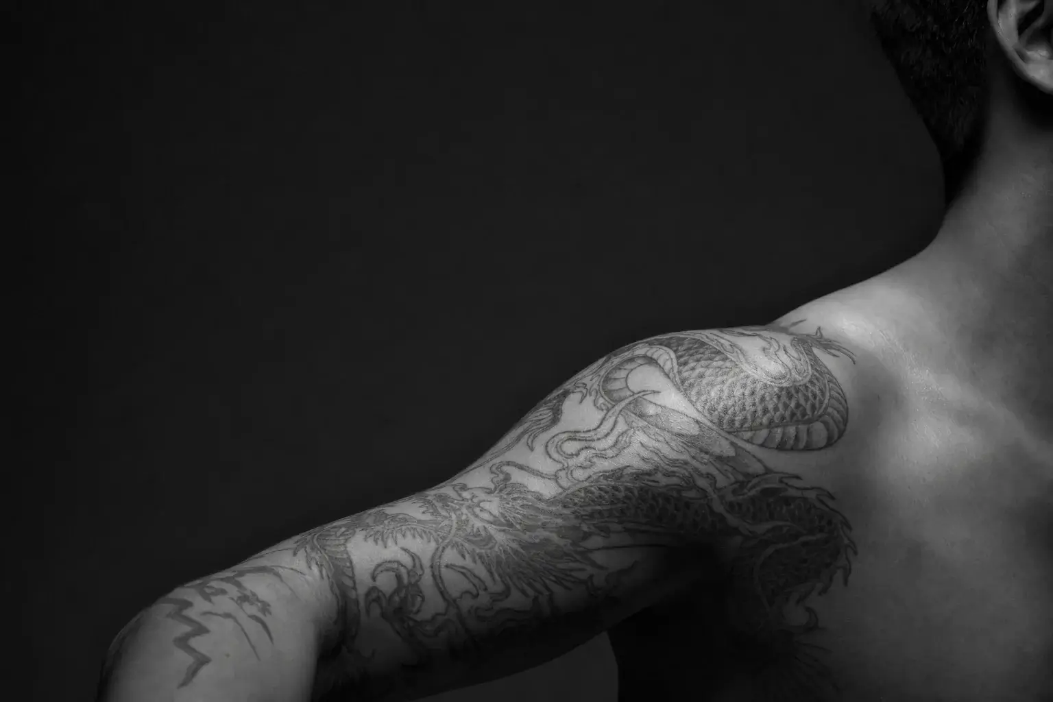 Tatouage dragon asiatique cicatrisé en noir et gris sur le bras