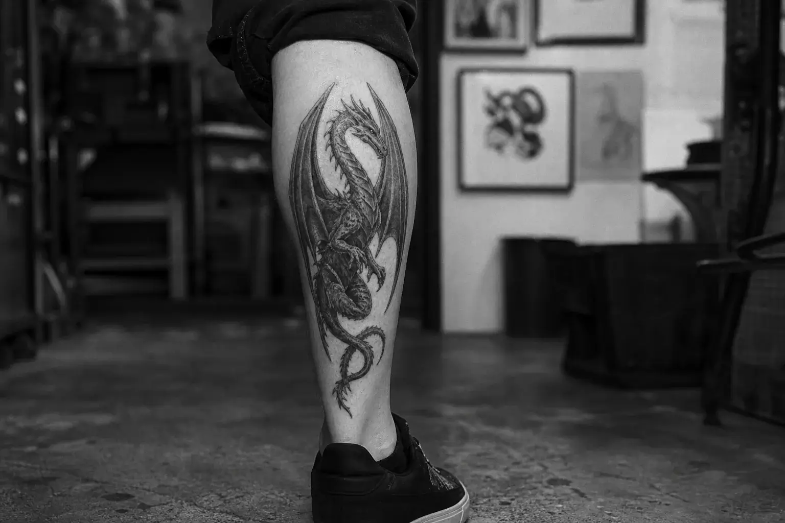 Tatouage dragon ailé cicatrisé en noir et gris sur le mollet